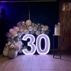 the number 30 is lit up in front of balloons