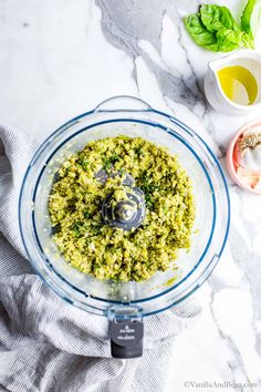 a food processor with pesto in it on a marble counter top next to other ingredients