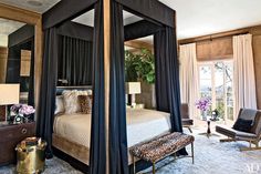 a bedroom with a four poster bed and leopard print foot stool in front of it