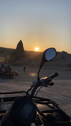 a motorcycle parked in the desert at sunset