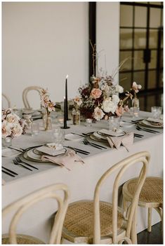 the table is set with place settings and flowers in vases, candles, and napkins