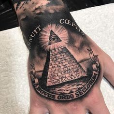 a hand with an all seeing pyramid tattoo on it