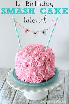 a pink frosted cake sitting on top of a white plate next to a bunting banner