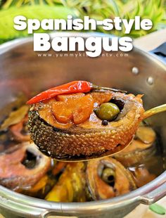 a spoon full of food sitting in a pot with the words spanish - style bangus above it