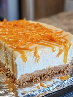 a piece of cheesecake with orange zest on top is sitting on tin foil