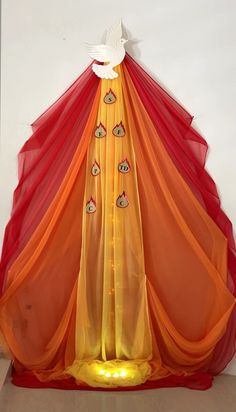 an orange and red canopy with white doves on the top in front of a wall