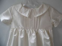 Inspired by a customers wedding gown, This infant baptism, blessing, christening gown is the ultimate in unisex gowns for my shop. The bodice has 6 pleats down the front with a pointed collar that reaches around to the back. The fabric is an off white shantung but can be done in cotton if requested. At 36 inches this is my longest gown and features a straight sleeve, gathered skirt, lining, and buttons in the back. LIMITED QUANTITIES Hat sold separately: https://www.etsy.com/listing/200586726/un Classic Dresses With Fitted Bodice For First Communion, Elegant Cream Baptism Dress For First Communion, Classic Fitted First Communion Dress, Elegant Fitted First Communion Dress, Classic Fitted Dress For Confirmation, Classic Fitted Dress For Baptism, Classic White Baptism Dress With Fitted Bodice, Elegant Cream Baptism Dress, Classic Wedding Gown With Pleated Bodice