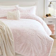 a hello kitty comforter set on a bed with pink sheets and pillowcases