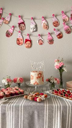 a table topped with cake and cupcakes covered in photos next to flowers on a string