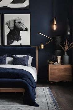 a bedroom with dark blue walls and artwork on the wall