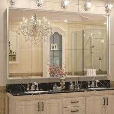 a bathroom with two sinks and a large mirror on the wall above it that has a chandelier in front of it