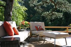 two chairs and a couch on a patio with trees in the backgrouf