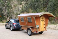 a car is parked next to a small trailer with a door on the front and side