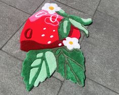 a close up of a rug on the ground with an apple and flower design painted on it