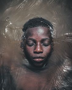 a young man is submerged in water with his eyes closed and head tilted to the side