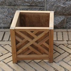 a wooden planter sitting on top of a brick floor next to a stone wall