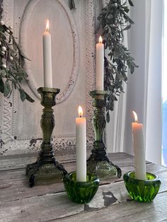 three candles are lit in green glass bowls