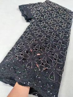 a woman's hand holding onto a black dress with sequins on it