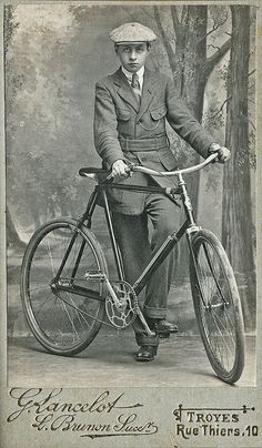 an old photo of a man on a bicycle with trees in the backgroud