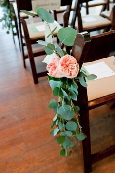 flowers are on the back of a chair at a wedding ceremony, with greenery in between them