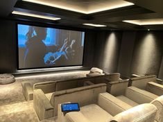 a home theater with couches and a projector screen in the middle of it