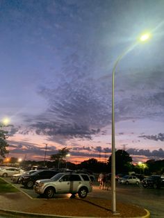 a parking lot filled with lots of parked cars under a cloudy blue sky at night