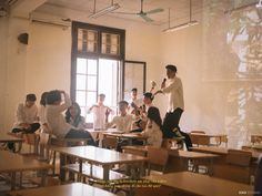 a classroom full of students sitting at desks and one teacher standing in front of the class room