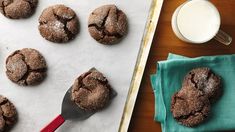 chocolate crinkle cookies sitting on top of a baking sheet next to a cup of milk