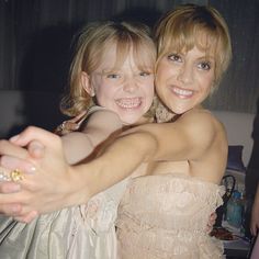 two young women hugging each other in front of a mirror with their arms around one another