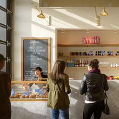 three people standing in front of a bakery counter