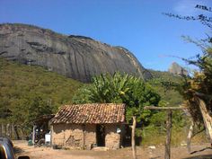 an old stone house in front of a mountain