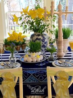 the table is set with blue and white dishes, flowers, and eggs on it