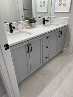 a bathroom with double sinks and large mirrors on the wall, along with white tile flooring