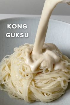 a white bowl filled with noodles covered in sauce being poured onto it's side