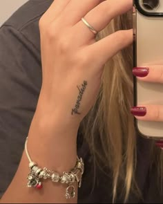 a woman holding up her cell phone to take a selfie with her wrist tattoo