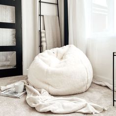 a white bean bag chair sitting on top of a carpeted floor next to a window