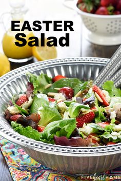 a salad in a bowl with strawberries on the side and lemons behind it