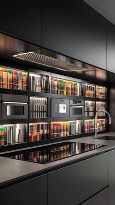 a kitchen with black cabinets and stainless steel counter tops is seen in this image, the shelves are full of spices