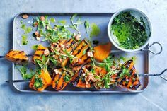 a metal tray topped with carrots next to a bowl of pesto and sauce