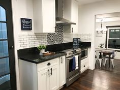 a kitchen with white cabinets and black counter tops, along with an island in the middle