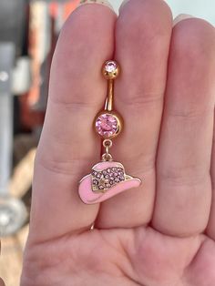 a person holding a pink and gold colored charm with a hat on it's side