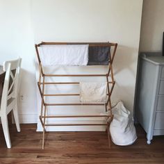 an ironing board and clothes rack in a small room with wood floors, white walls and hardwood flooring