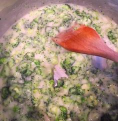 broccoli and onions cooking in a pot with a red wooden spoon on the side