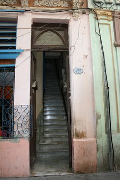 an old building with stairs leading up to the second floor and another door on one side