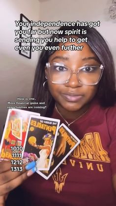 a woman wearing glasses holding up some cards