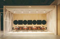 an empty room with chairs and tables in front of a large sign on the wall