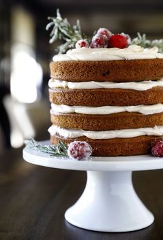 a cake with white frosting and cranberries on top sitting on a table