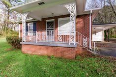 a brick house with white railings on the front porch and green grass around it