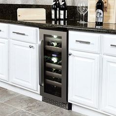 a wine cooler in the middle of a kitchen counter with bottles and glasses on it