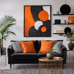 a living room with black couches, orange pillows and modern art on the wall